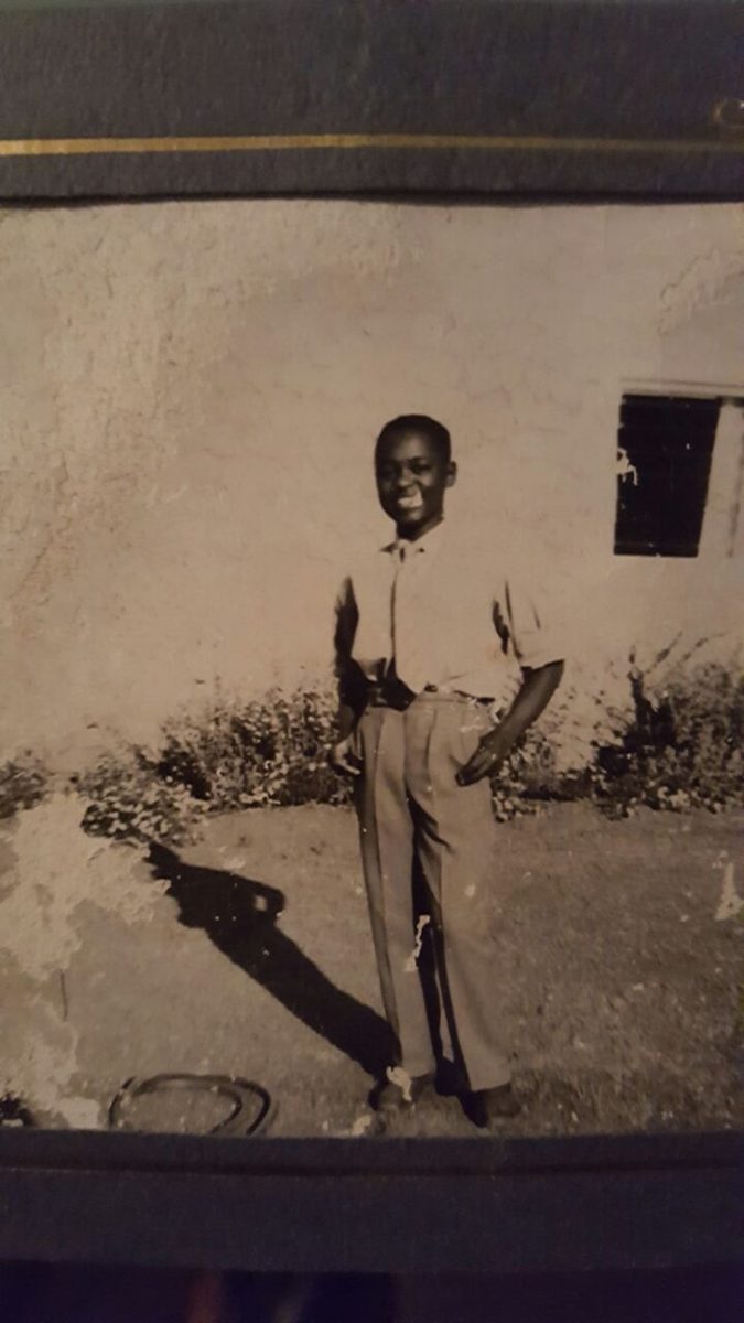Black and white photo of a smiling boy standing in a garden