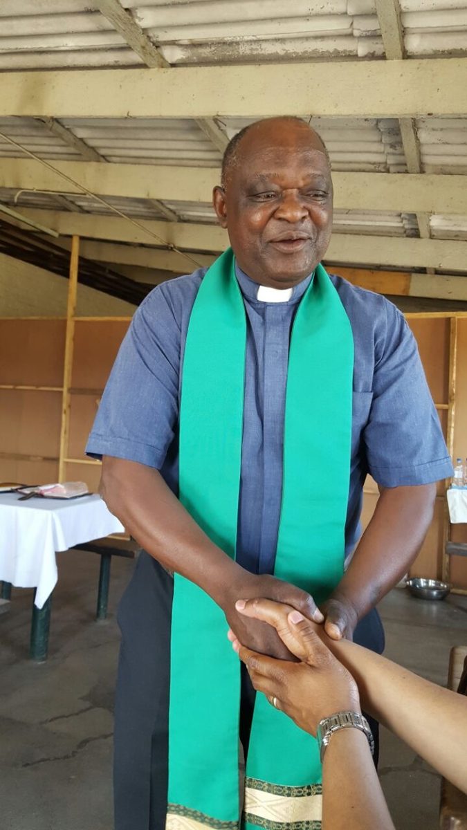 Smiling man in a green stole shaking hands